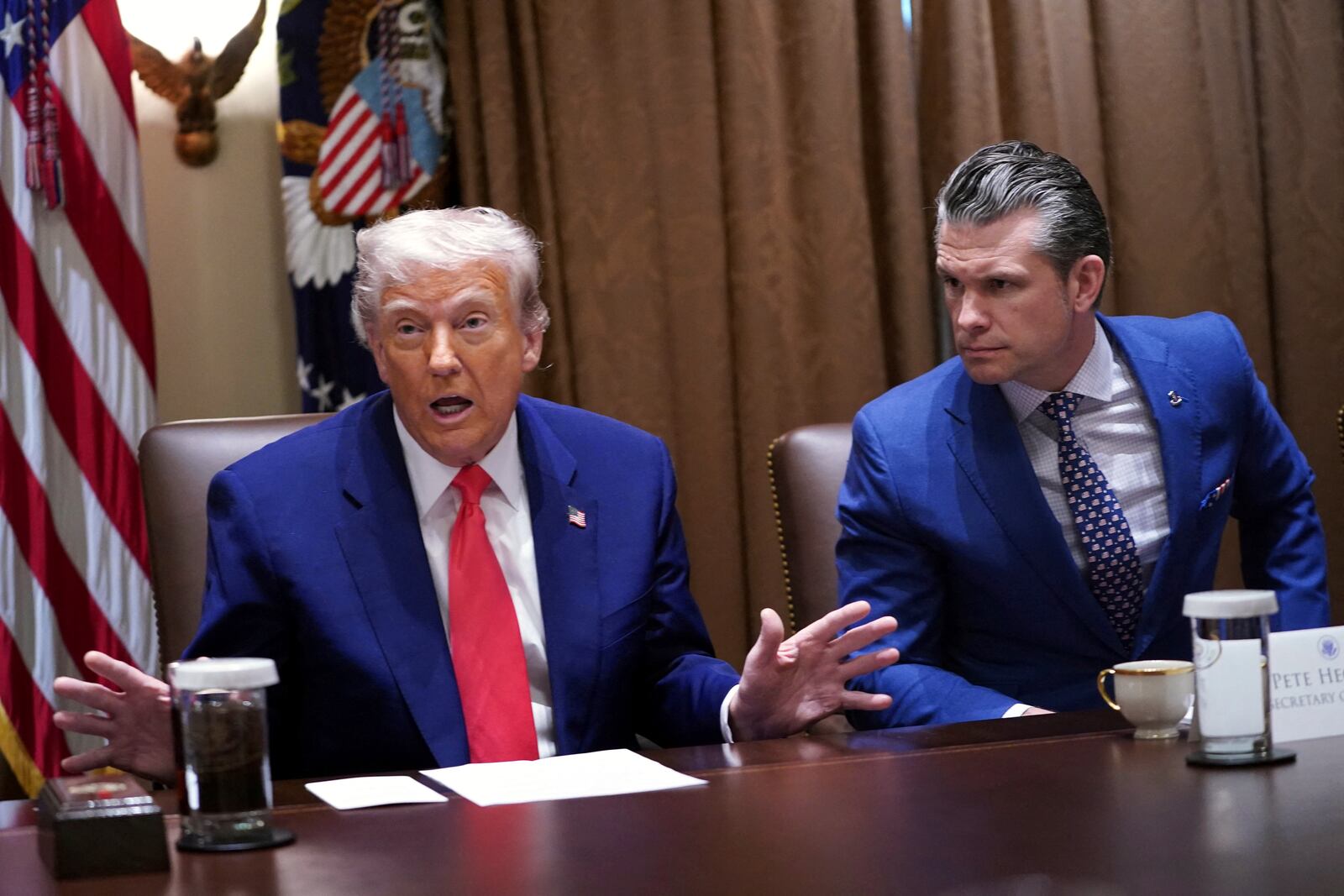 President Donald Trump speaks as Defense Secretary Pete Hegseth listens at a cabinet meeting in the Cabinet Room of the White House, Thursday, April 10, 2025, in Washington. (Pool via AP)