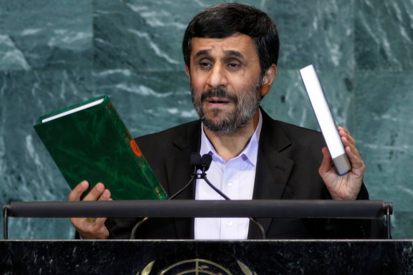 FILE - Iran's President Mahmoud Ahmadinejad, President of Iran, holds up a copies of the Quran, left, and Bible, right, as he addresses the 65th session of the United Nations General Assembly at U.N. headquarters, Sept. 23, 2010, during a speech where he prompted walkouts from the assembly when he questioned whether the Sept. 11 attacks were staged. (AP Photo/Richard Drew, File)
