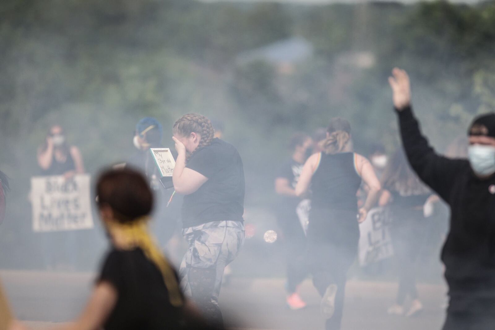 Protesters react to tear gas used by police officers to clear the intersection of North Fairfield Road and Pentagon Boulevard on Monday in Beavercreek. JIM NOELKER/STAFF