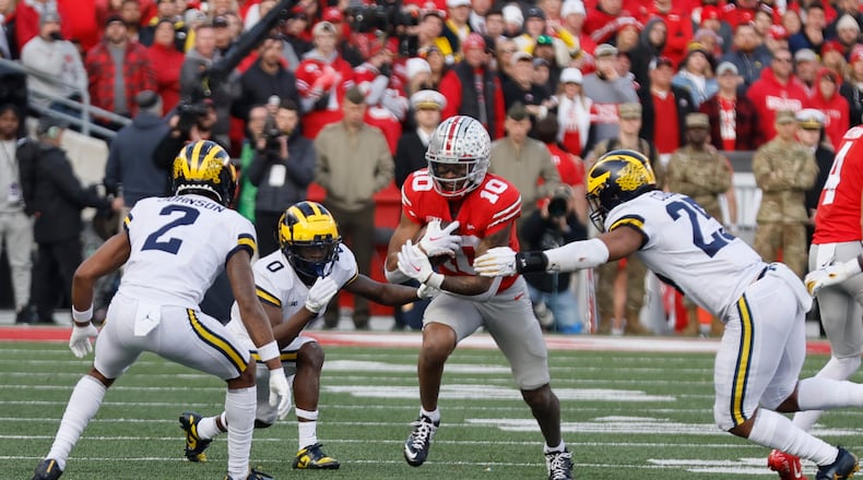 Ohio State receiver Xavier Johnson, center, tries to run between Michigan defenders during the second half of an NCAA college football game on Saturday, Nov. 26, 2022, in Columbus, Ohio. (AP Photo/Jay LaPrete)