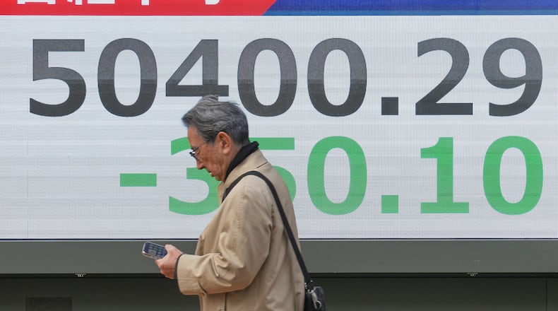 A person walks in front of an electronic stock board showing Japan's Nikkei index at a securities firm, Monday, Dec. 29, 2025, in Tokyo. (AP Photo/Eugene Hoshiko)