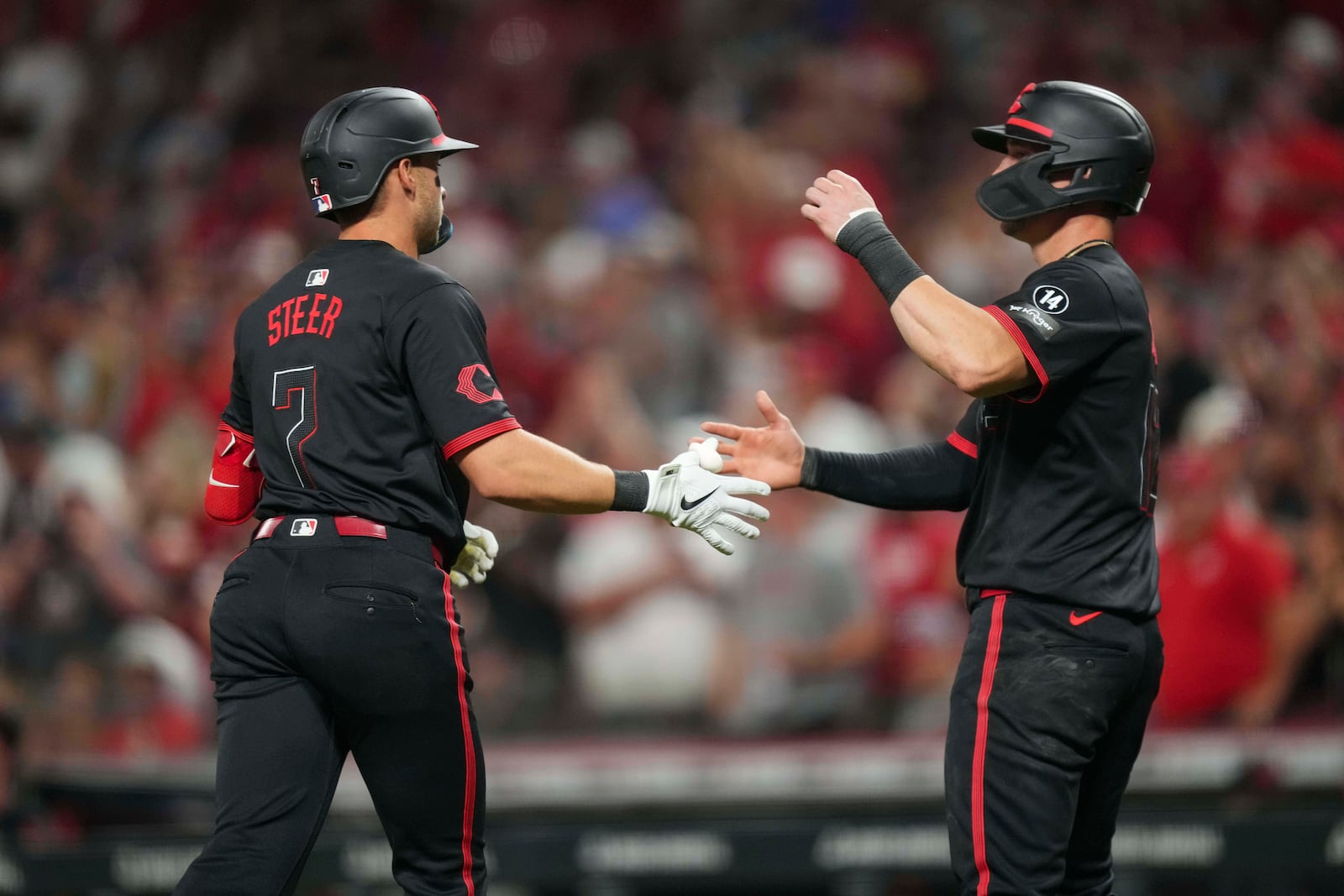 Cincinnati Reds' Spencer Steer (7) celebrates with teammate Austin Hays after hitting a two-run home run during the sixth inning of a baseball game against the Chicago Cubs, Friday, Sept. 19, 2025, in Cincinnati. (AP Photo/Jeff Dean)