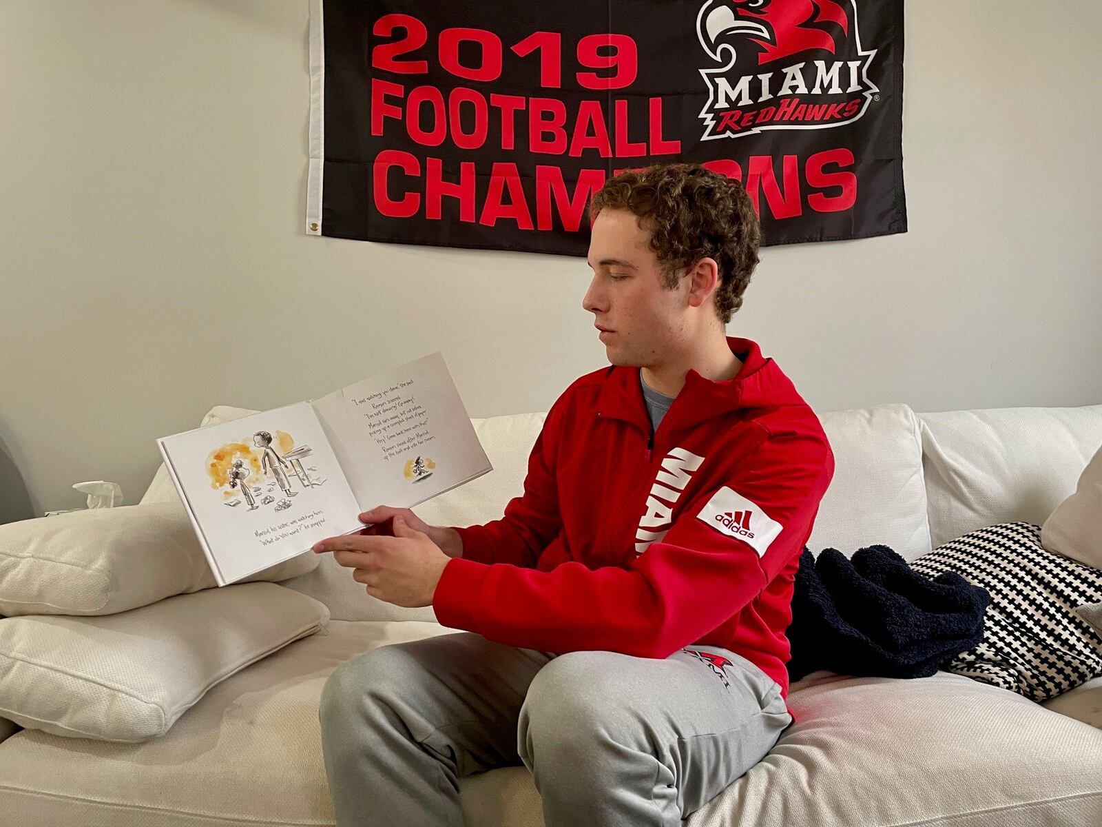 Miami University football player Henry Beckett invented a new reading program involving himself and other university athletes to reach out to students in the adjacent Talawanda School system. Beckett, shown here during one of his video recordings of reading remotely to school kids, plans to recruit more Miami athletes to become regular members of his "Redhawk Readers." (Provided Photo\Journal-News)