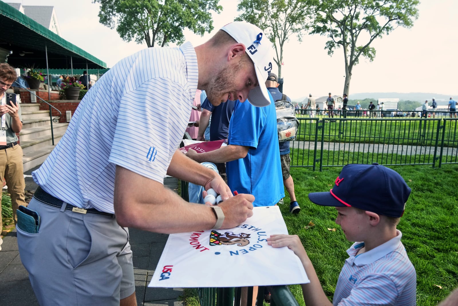 Matt Vogt, right, signs autographs for fans as he makes his way to the first tee for a practice round for the 2025 US Open golf championship at Oakmont Country Club in Oakmont, Pa. Monday, June 9, 2025. (AP Photo/Gene J. Puskar)