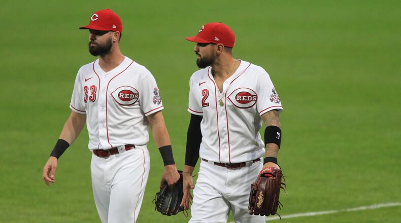 Jesse Winker, left, and Nick Castellanos return to the dugout after warming up before a game against the Indians on Monday, Aug. 3, 2020, at Great American Ball Park in Cincinnati. David Jablonski/Staff