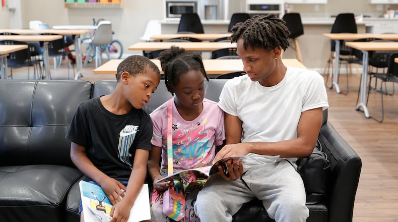FILE - Karter Hardeman, 7, left, and Janayla Ralsey, 8, center, read with volunteer Joshua Banks, right, during an after-school literacy program through the Pure Hope Project in Atlanta on Thursday, April 6, 2023. (AP Photo/Alex Slitz, File) null