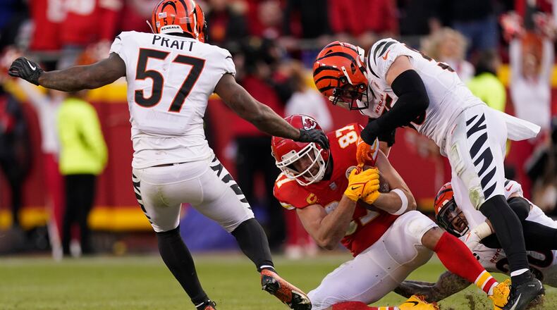 Kansas City Chiefs tight end Travis Kelce (87) catches a pass between Cincinnati Bengals linebacker Germaine Pratt (57) and linebacker Logan Wilson, right, during the second half of the AFC championship NFL football game, Sunday, Jan. 30, 2022, in Kansas City, Mo. (AP Photo/Charlie Riedel)