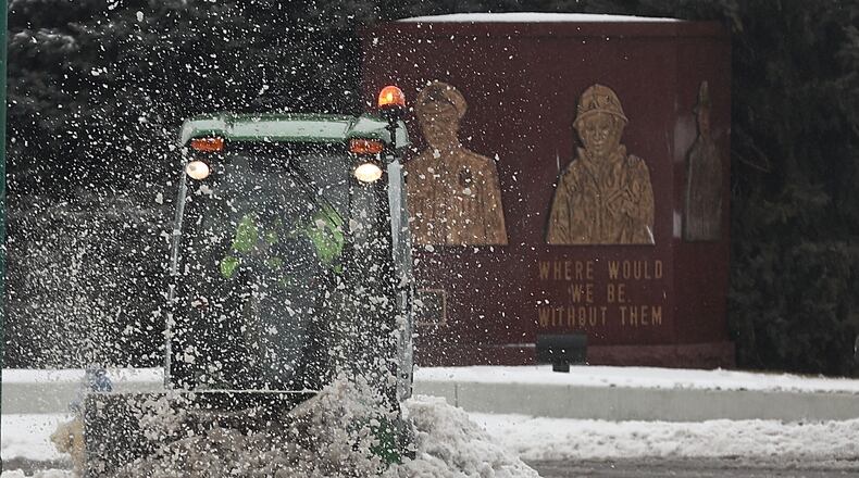 A worker cleans the snow and slush off the sidewalk surrounding the Clark County Courthouse Sunday. BILL LACKEY/STAFF