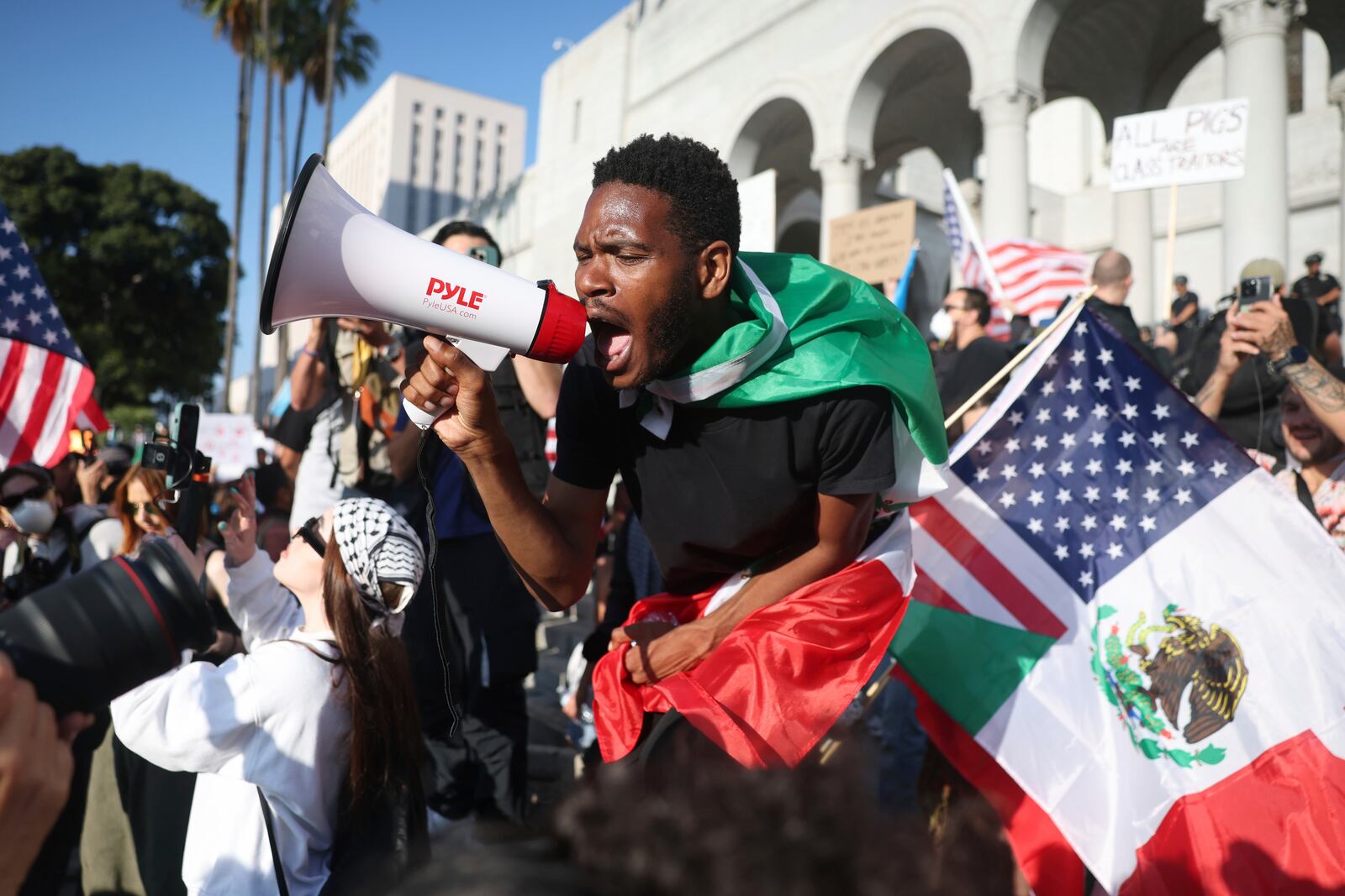 A man shouts into a megaphone outside City Hall during a protest on Wednesday, June 11, 2025, in Los Angeles. (AP Photo/Ethan Swope)
