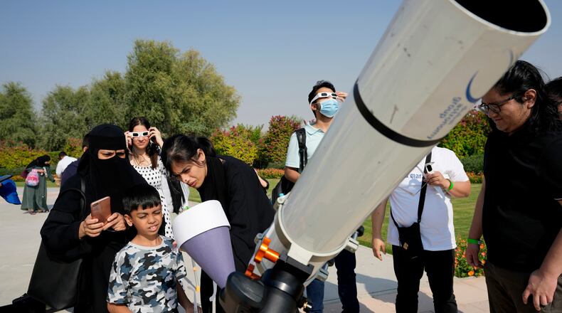 People watch a partial solar eclipse wearing special glasses at the Al Thuraya Astronomy Center, in Dubai, United Arab Emirates, Tuesday, Oct. 25, 2022. (AP Photo/Kamran Jebreili)