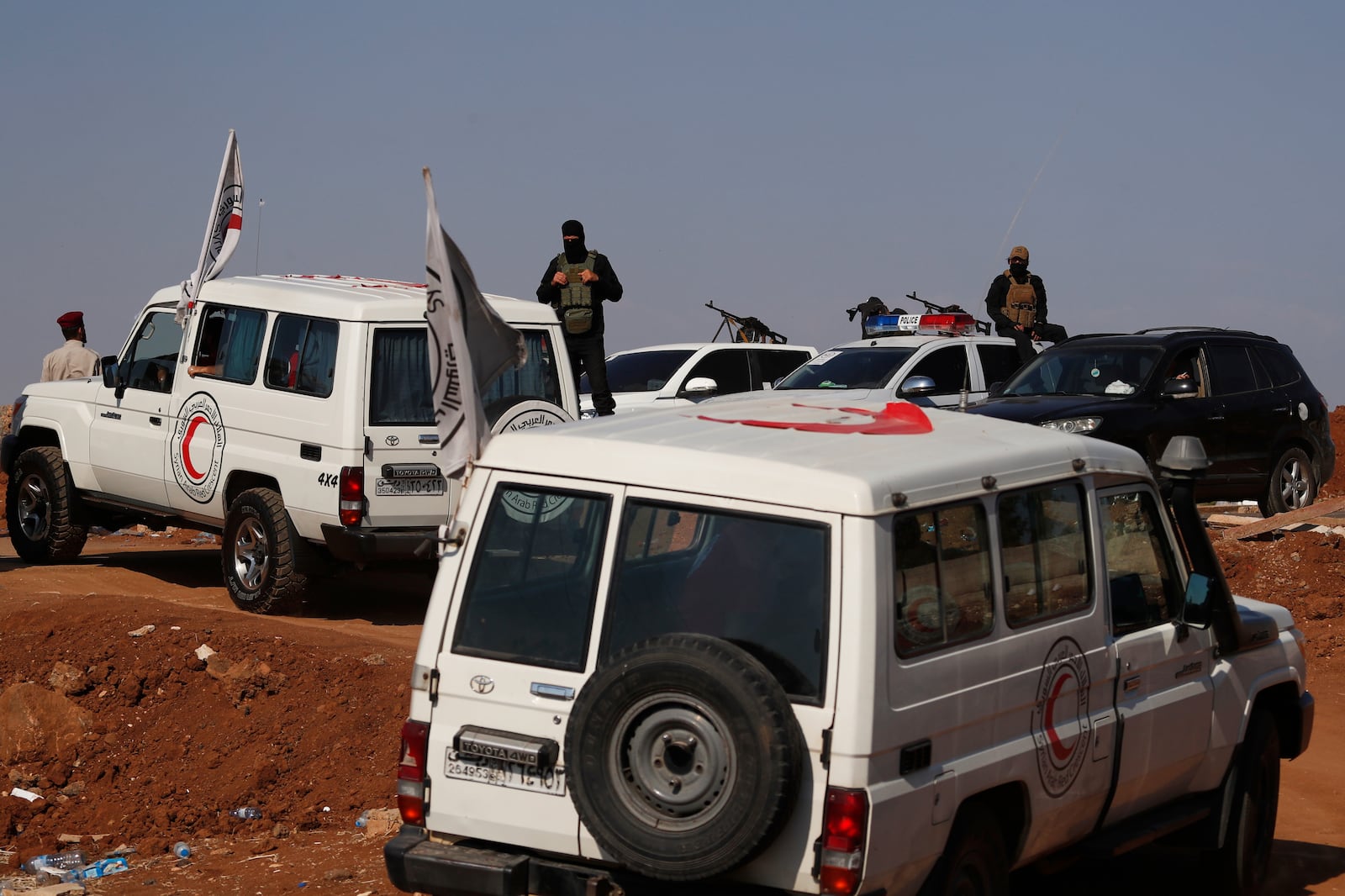 A convoy of ambulances and buses arrives at a checkpoint in the village of Busra al-Harir, southern Syria, on its way to Sweida province, as security forces cordon off the area to block Bedouin fighters from entering the province, Tuesday, July 22, 2025. (AP Photo/Omar Sanadiki)