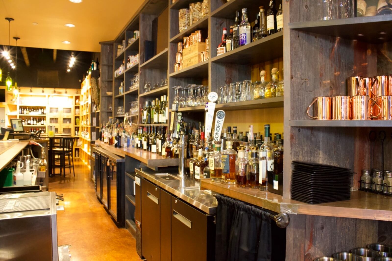 The bar at Cru Gastro Lounge is made from reclaimed barn wood. While the restaurant is known for its wine, other options like bourbon are also popular.