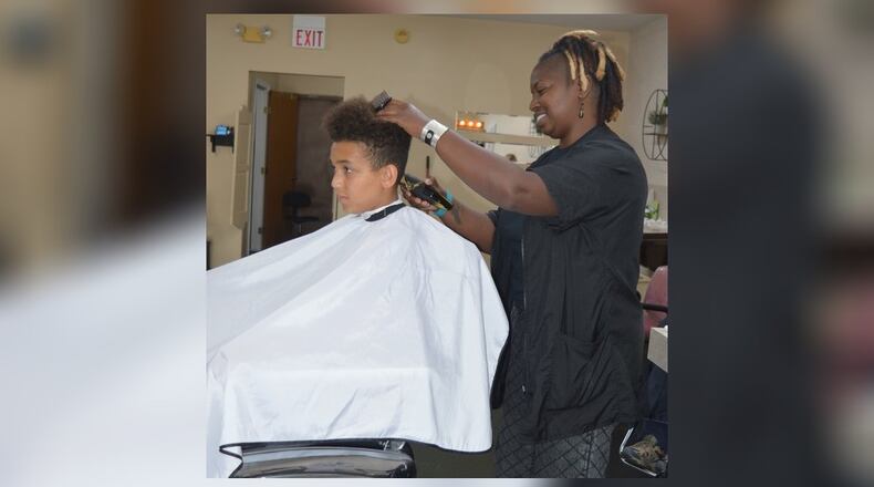 Jiolvanni Henegar sits in the barber chair while Juiquetta Harmon, known as Kiki the barber, cuts his hair. BOB RATTERMAN/CONTRIBUTED