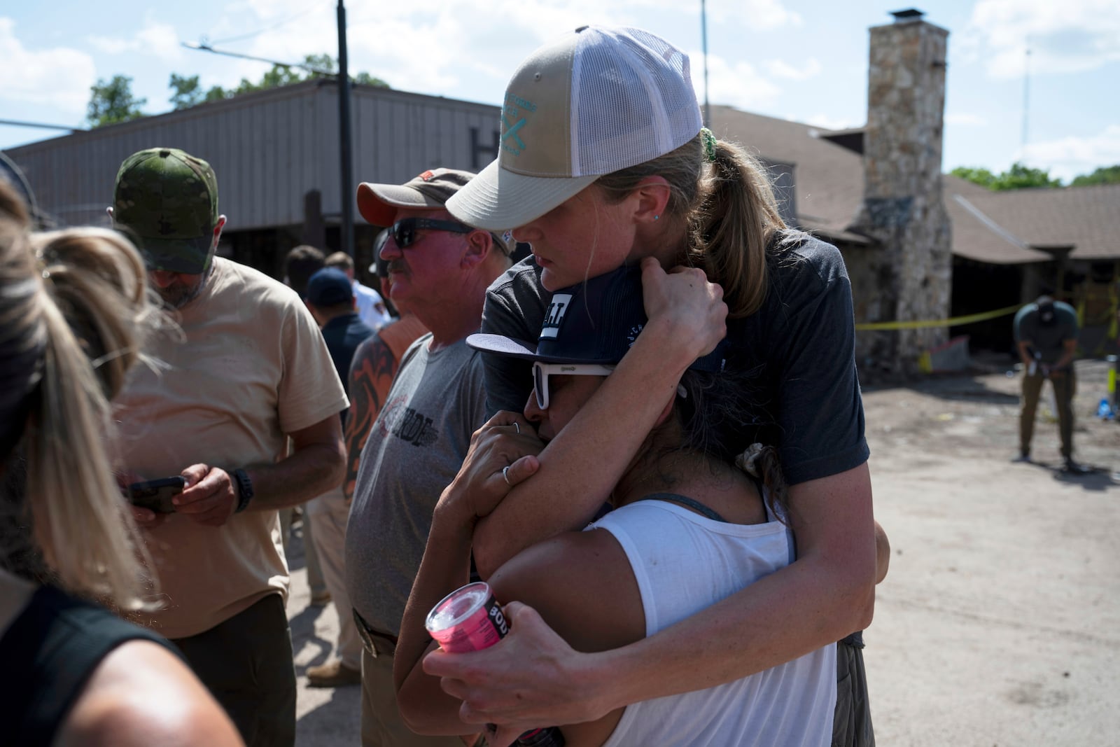 Volunteers helping in search and recovery efforts embrace during a press conference on Tuesday, July 8, 2025, in Hunt, Texas. (AP Photo/Eli Hartman)