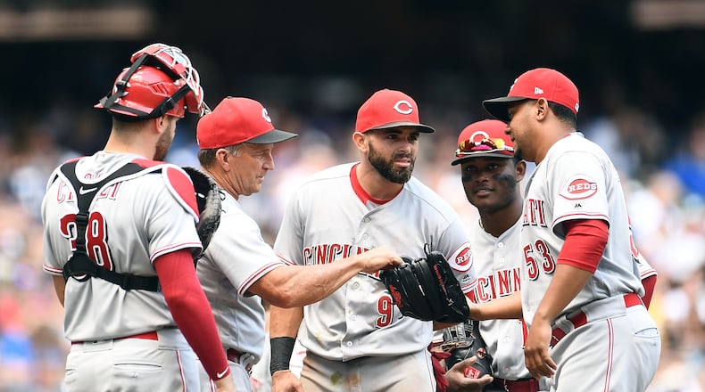 MILWAUKEE, WI - AUGUST 22:  Head coach Jim Riggleman #35 of the Cincinnati Reds hands the ball to Wandy Peralta #53 during the sixth inning of a game against the Milwaukee Brewers at Miller Park on August 22, 2018 in Milwaukee, Wisconsin.  (Photo by Stacy Revere/Getty Images)