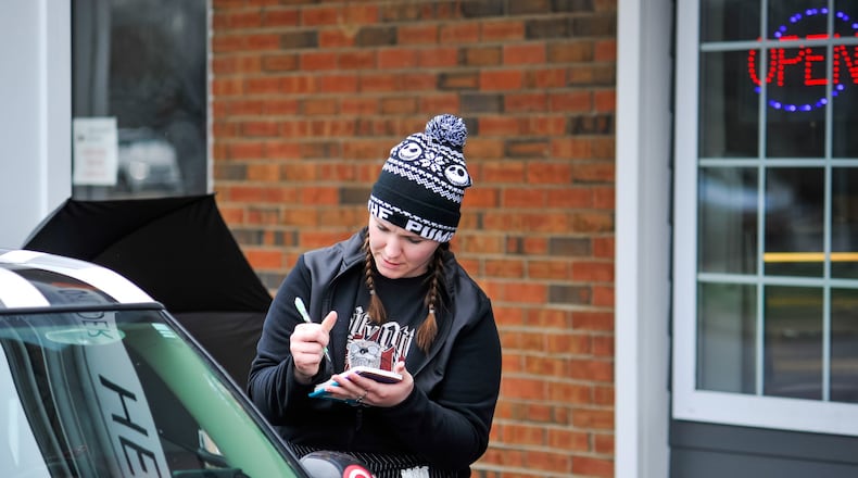 Elizabeth Nash-Pittman takes an order at what would be the front door at Lindenwald Station restaurant Wednesday, March 18, 2020, on Pleasant Avenue in Fairfield. The state has banned all dine-in food consumption to help reduce the spread of coronavirus. Lindenwald Station is offering carhop style serving with call-in and drive-up orders to try to keep employees working and customers served. NICK GRAHAM/STAFF