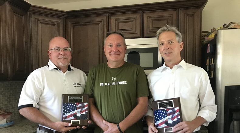 Tri-State Heating and Cooling President Keith Adams (left) and Huff Realty Senior Sales Vice President Scot Avery (right) hold the plaques retired Navy Chief Petty Officer Leonard Koebbe (center) gave them for helping him move into his new home. STAFF/EMMA STIEFEL