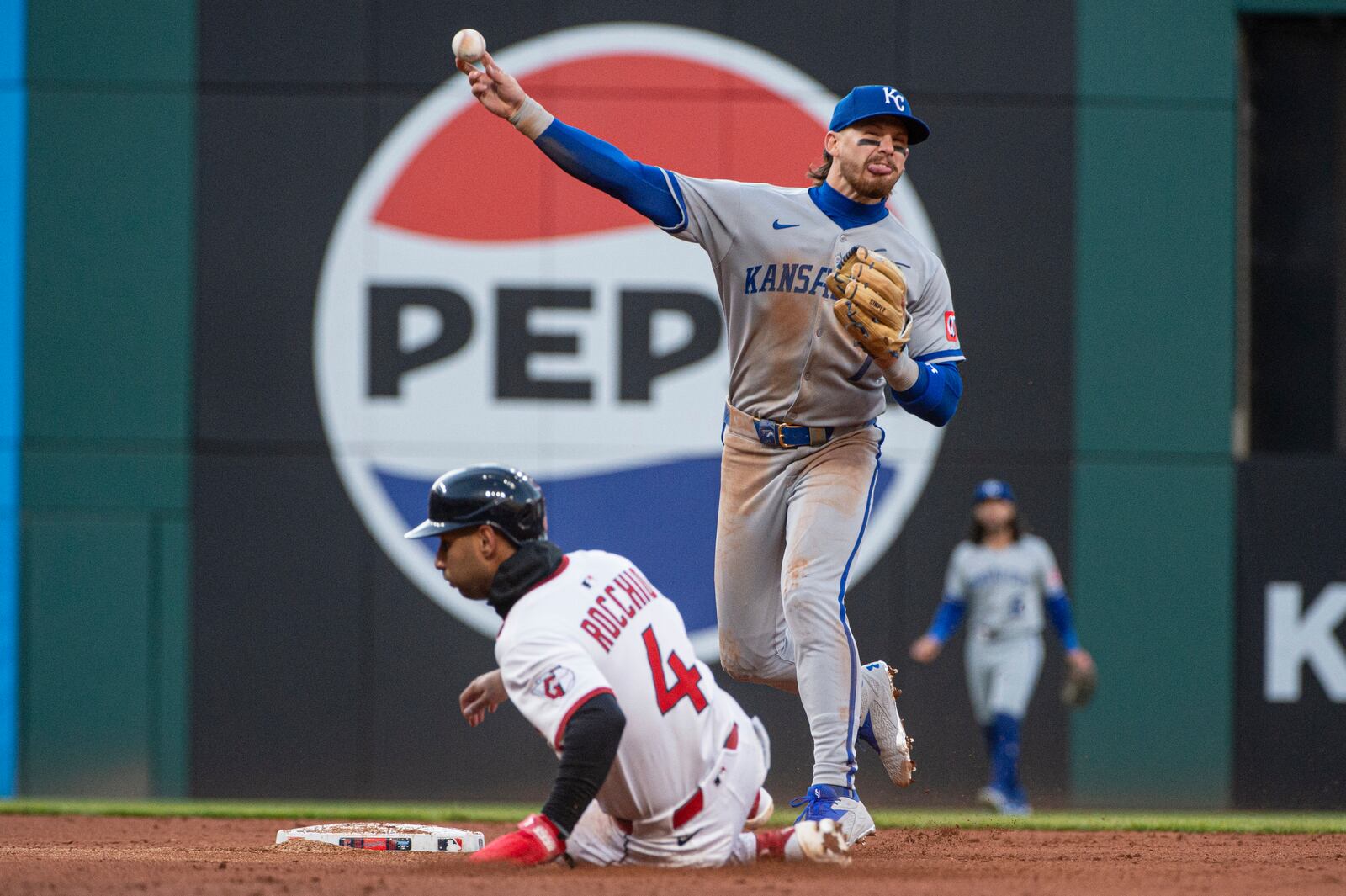 Kansas City Royals' Bobby Witt Jr., right, throws to first base after forcing out Cleveland Guardians' Brayan Rocchio (4) during the fifth inning of a baseball game in Cleveland, Saturday, April 12, 2025. (AP Photo/Phil Long)