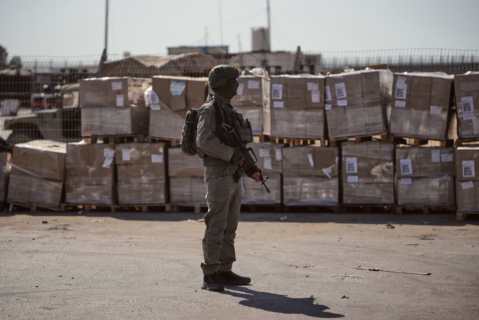 An Israeli soldier stands beside humanitarian aid packages awaiting pickup on the Palestinian side of the Kerem Shalom crossing in the Gaza Strip, Thursday, July 24, 2025. during a media tour organized by the Israeli army. (AP Photo/Ohad Zwigenberg)