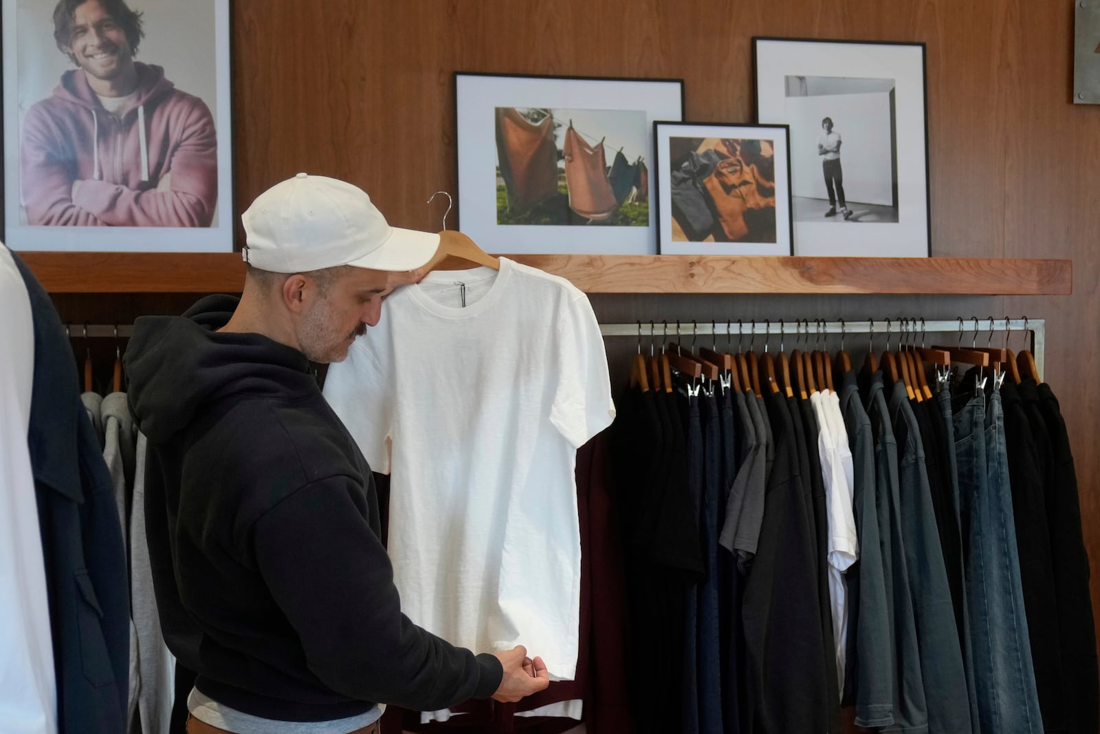 Javid Moghaddasnia, Director of Customer Engagement, holds up an American Giant shirt while being interviewed at the company's showroom in San Francisco, Thursday, April 17, 2025. (AP Photo/Jeff Chiu)