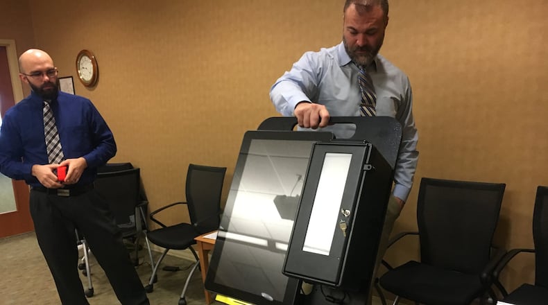 Butler County Board of Elections board member Todd Hall reviews an electronic voting machine on Monday morning, at the board office in Princeton Road in Hamilton. MICHAEL D. PITMAN/STAFF
