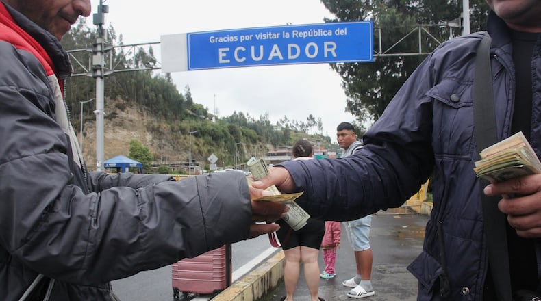 People exchange currencies at the Rumichaca international bridge between Colombia and Ecuador in Rumichaca, Colombia, Thursday, Jan. 22, 2026. (AP Photo/Leonardo Castro)