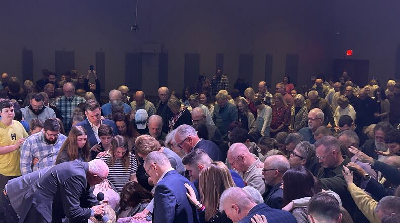 Berachah Church leaders and members lay their hands on Pastor Luke Ferrell Sunday during his ordination ceremony at the church. His father, Lamar Ferrell, is pastor of the Middletown church, and his late grandfather, Lewis Ferrell, started the church in a Springboro basement 35 years ago. RICK McCRABB/CONTRIBUTOR