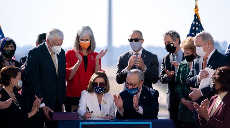House Speaker Nancy Pelosi (D-Calif.), alongside Senate Majority Leader Chuck Schumer (D-N.Y.), signs the COVID-19 relief bill during an enrollment ceremony outside the Capitol in Washington, with the Washington Monument in the background, on Wednesday, March 10, 2021. Congress gave final approval on Wednesday to President Joe Biden’s sweeping, nearly $1.9 trillion stimulus package, as Democrats acted over unified Republican opposition to push through an emergency pandemic aid plan that included a vast expansion of the country’s social safety net. (Stefani Reynolds/The New York Times)