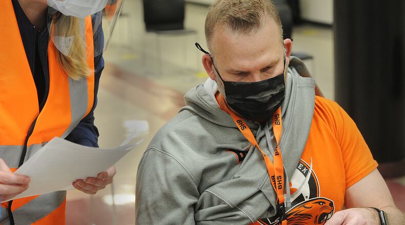 Dale Wren, principal for Beavercreek High Scool reads over information handed to him by Christi Hammonds, left,  about receiving the COVID-19 vaccination Thursday, Feb. 18, 2021 at the high school. MARSHALL GORBY\STAFF