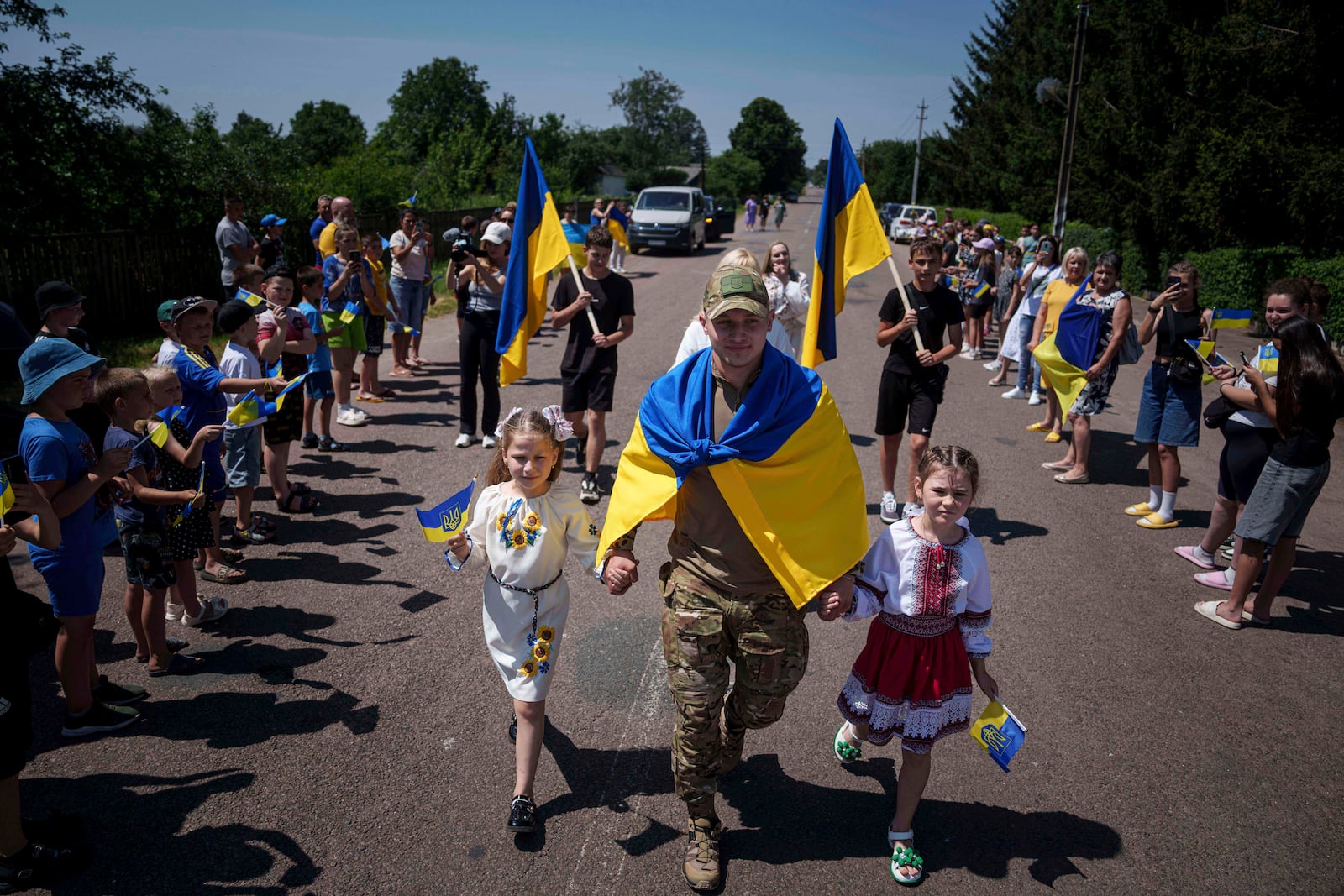 Ukrainian soldier Denys Zalizko, 21, walks though his fellow villagers after returning from Russian captivity in Holovyno, Zhytomyr region, Ukraine, Monday, July 7, 2025. (AP Photo/Evgeniy Maloletka)