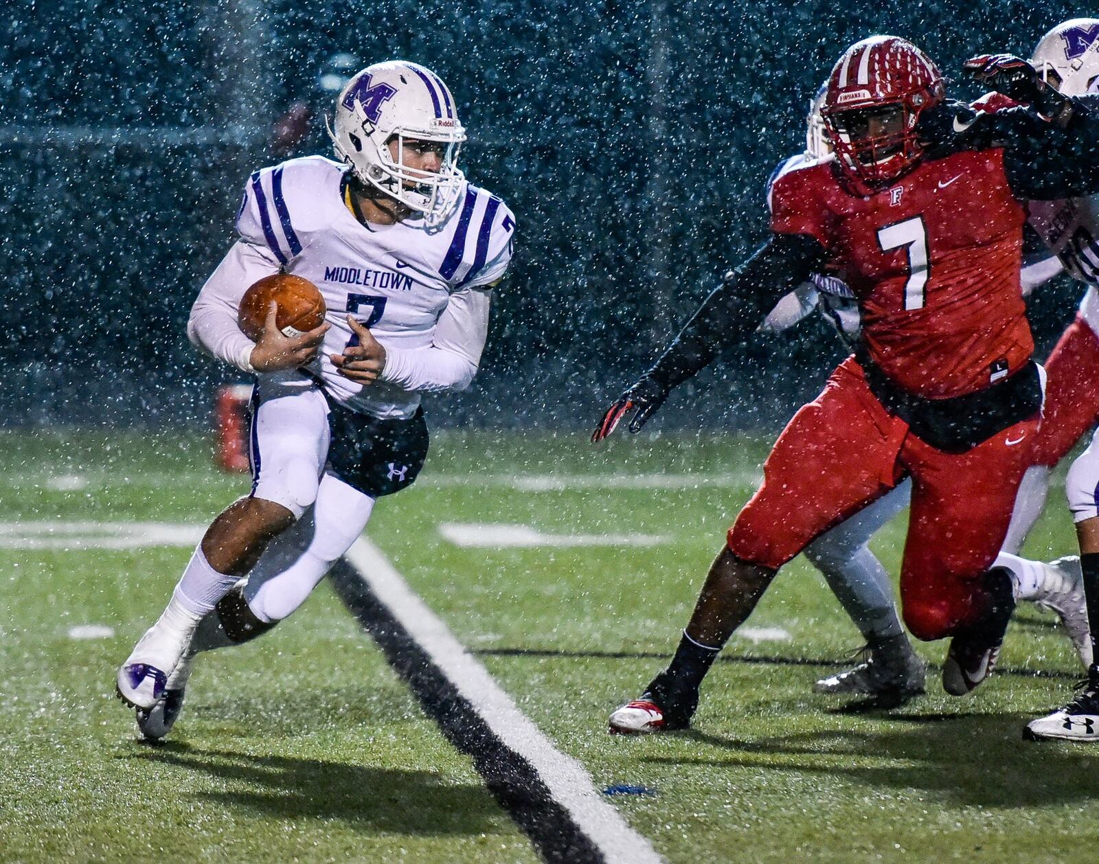 Middletown quarterback Blake Marshall (7, white) tries to elude Fairfield’s Malik Vann (7, red) during Friday night’s game at Fairfield Stadium. NICK GRAHAM/STAFF