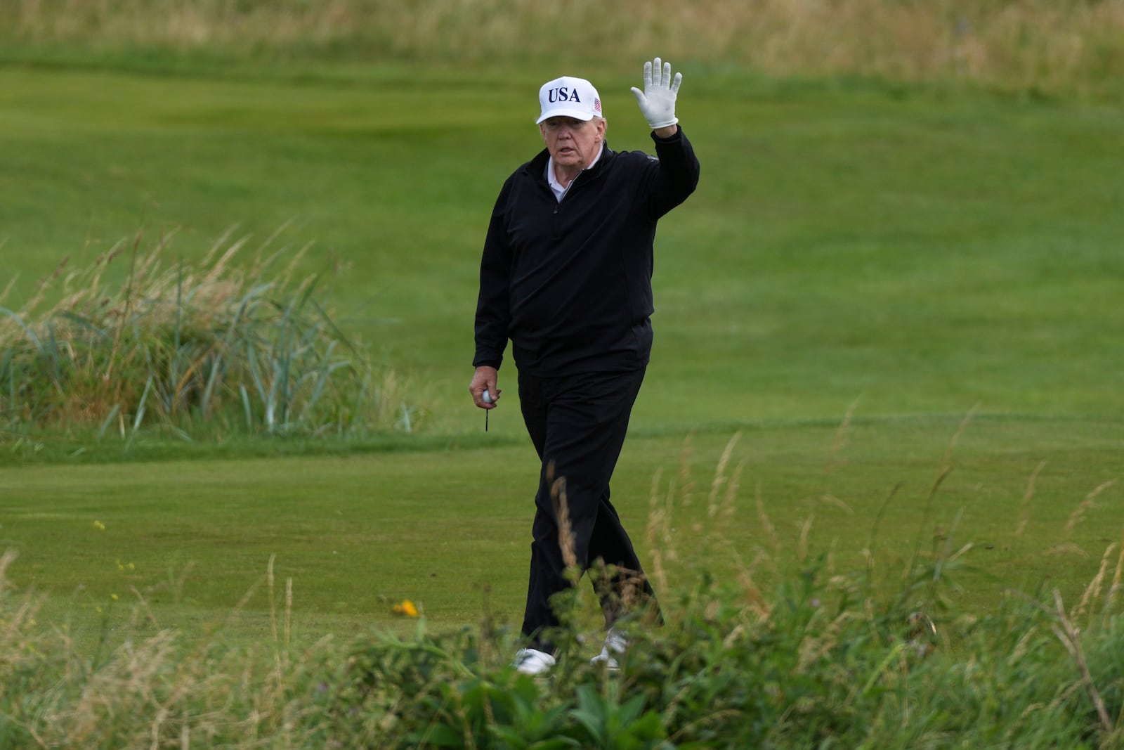 President Donald Trump waves to reporters as he plays golf at the Trump Turnberry golf course in Turnberry, Scotland, Saturday, July 26, 2025.(AP Photo/Alastair Grant)