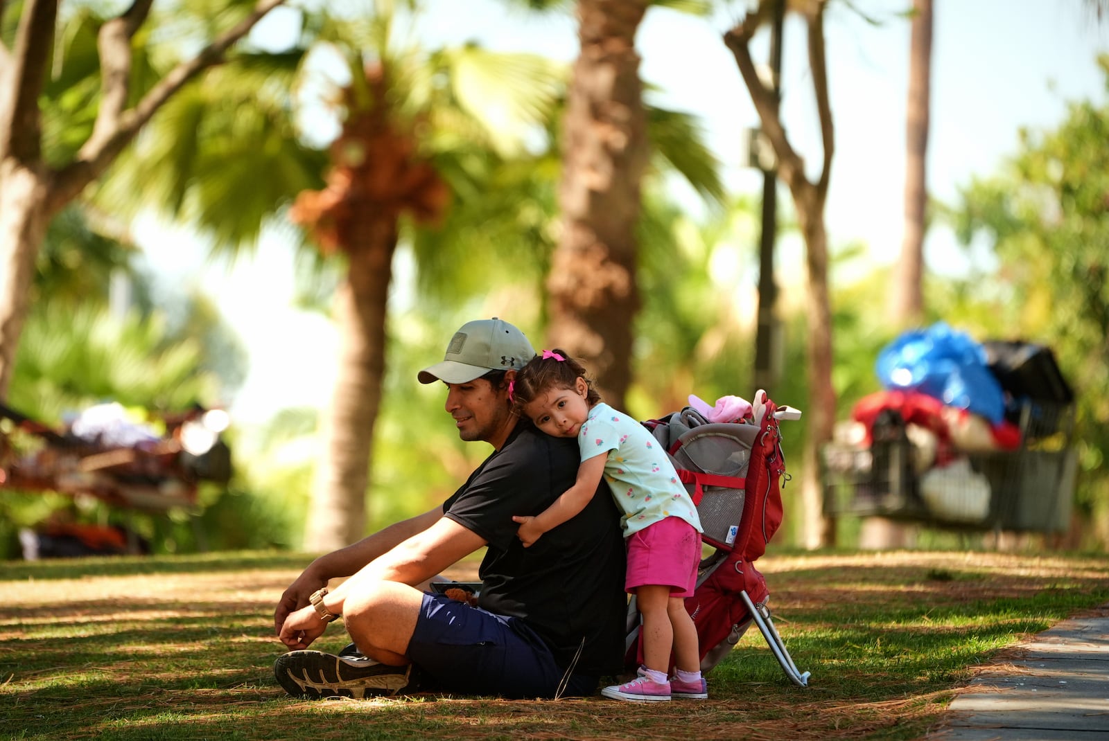 Miguel Hernandez is hugged by his one-year-old daughter Sayreli at MacArthur Park, Tuesday, July 8, 2025, in Los Angeles. (AP Photo/Damian Dovarganes)