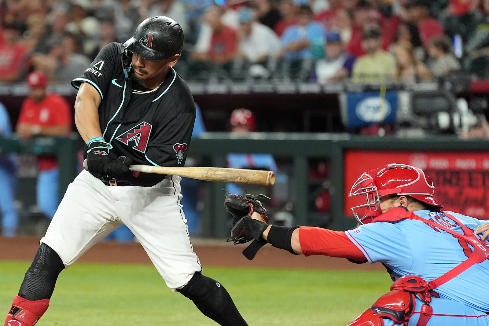 Arizona Diamondbacks' Josh Naylor, left, starts his swing on a catcher interference with St. Louis Cardinals catcher Pedro Pagés during the first inning of a baseball game Saturday, July 19, 2025, in Phoenix. (AP Photo/Ross D. Franklin)