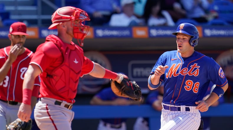 New York Mets' Hayden Senger (98) scores behind Washington Nationals catcher Chris Herrmann, left, in the fifth inning of a spring training baseball game, Saturday, March 26, 2022, in Port St. Lucie Fla. (AP Photo/Sue Ogrocki)