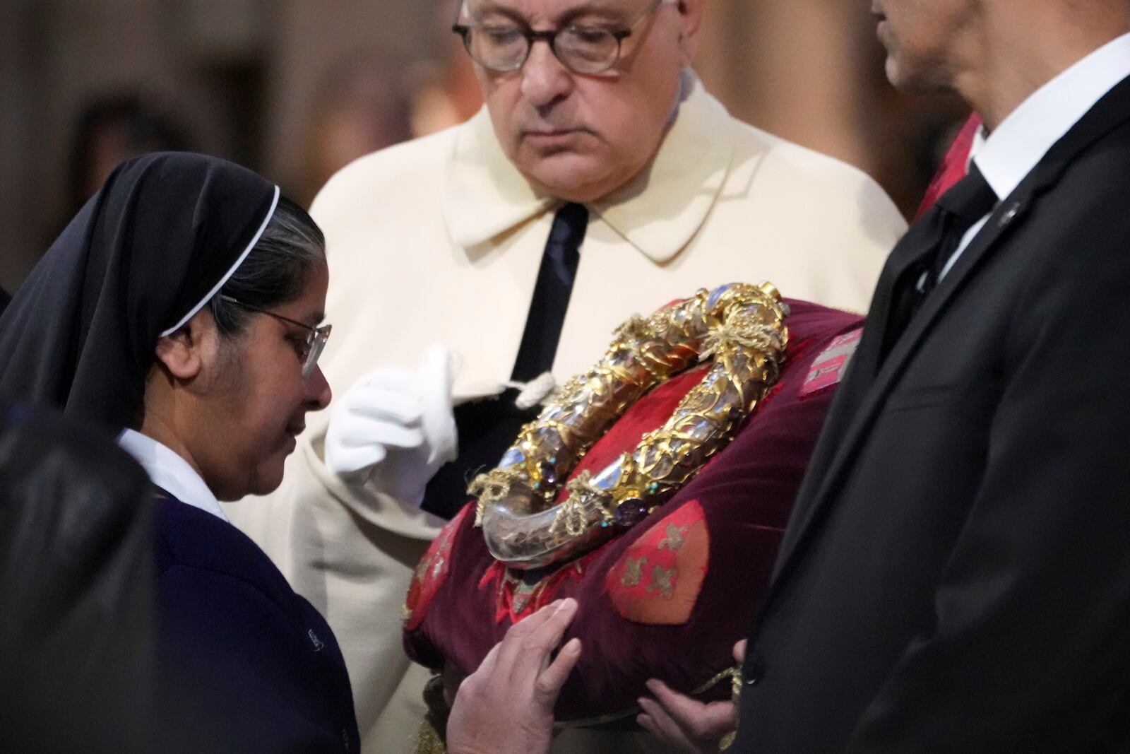 A nun touches the ancient relic that many Christians revere as Jesus Christ's "Crown of Thorns" during a ceremony to mark Good Friday at Notre Dame cathedral, Friday, April 18, 2025 in Paris. (AP Photo/Michel Euler)