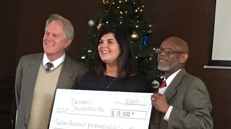 Ami Vitori, center, presents a $12,500 check to Phillip Harrison, left, board present of Downtown Middletown Inc., and Jeff Payne, DMI executive director. She won a $25,000 grant from Starbucks and split the grant between DMI and Community Building Institute. RICK McCRABB/STAFF