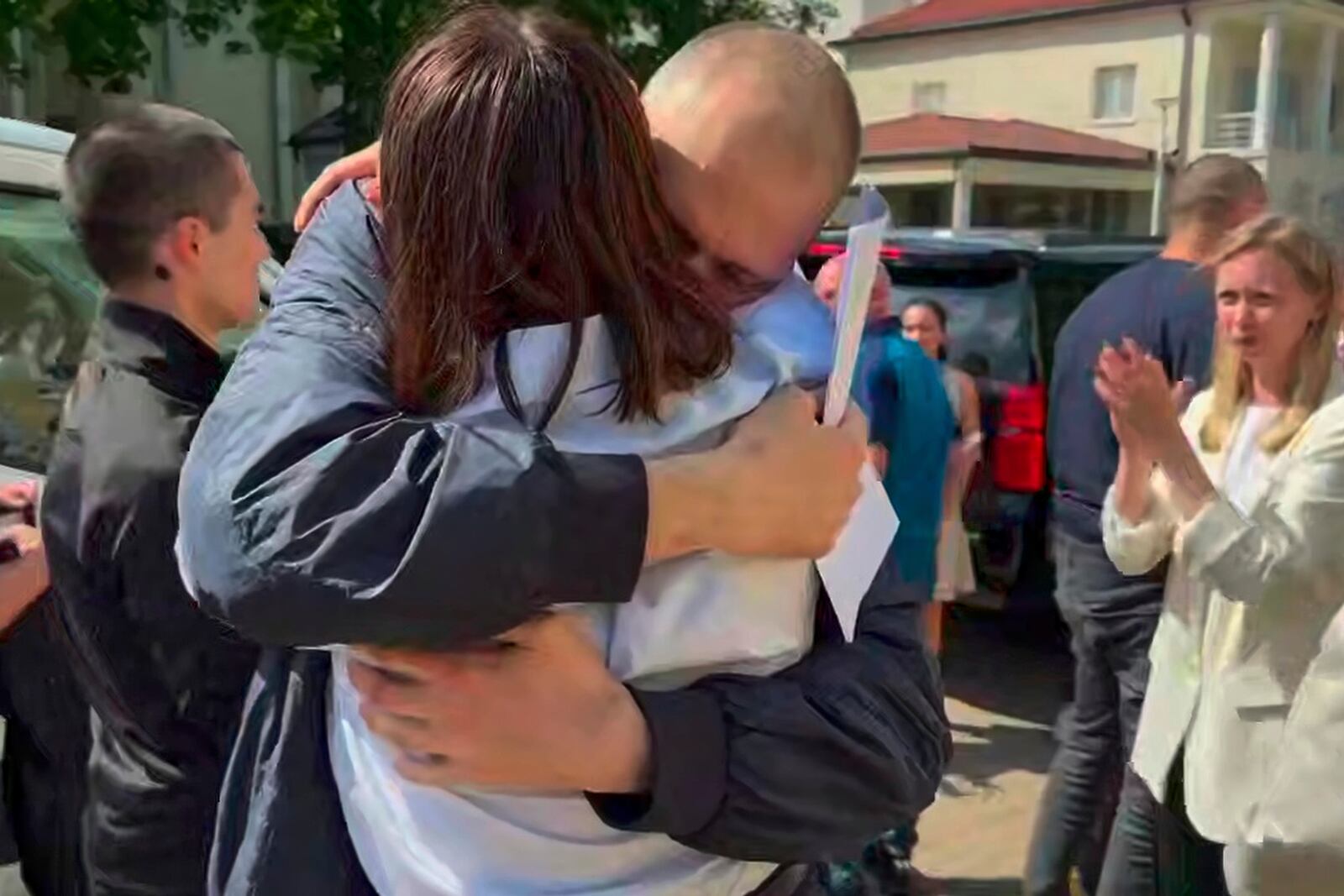 This photo taken from video released by Sviatlana Tsikhanouskaya Office on Saturday, June 21, 2025, shows Sviatlana Tsikhanouskaya, back to a camera, hugging her husband Syarhei Tsikhanouski, center, during their meeting at the U.S. Embassy in Vilnius, Lithuania, Saturday, June 21, 2025. (Sviatlana Tsikhanouskaya Office via AP)