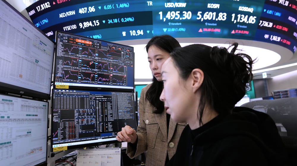 Currency traders watch monitors near a screen showing the Korea Composite Stock Price Index (KOSPI), top center, and the foreign exchange rate between U.S. dollar and South Korean won, top center left, at the foreign exchange dealing room of the Hana Bank headquarters in Seoul, South Korea, Tuesday, March 24, 2026. (AP Photo/Ahn Young-joon)