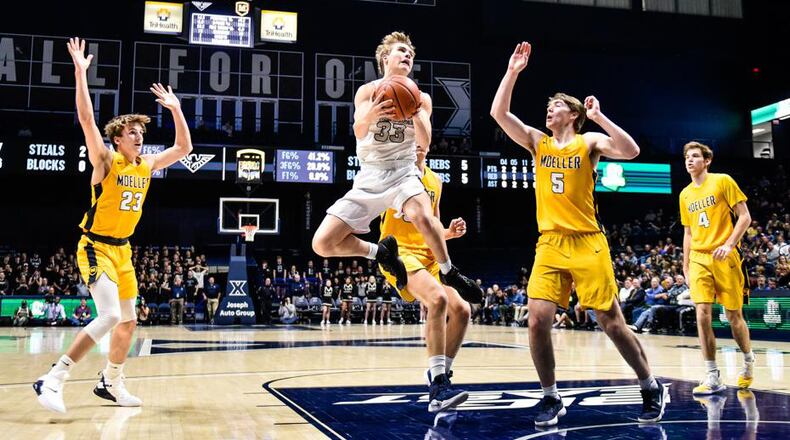 Lakota East’s Grant Spicer (33) drives between Moeller’s Will McCracken (23) and Alec Pfriem (5) during a Division I regional basketball semifinal Wednesday night at Xavier University’s Cintas Center. Moeller won 47-33. NICK GRAHAM/STAFF