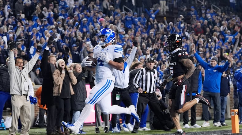 BYU running back LJ Martin (4) scores a touch down past Cincinnati safety Christian Harrison (5) during the second half of an NCAA college football game, Saturday, Nov. 22, 2025, in Cincinnati. (AP Photo/Carolyn Kaster)