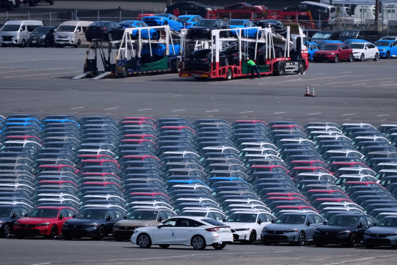 FILE - Workers, back, unload vehicles while a car, center front, is moved to another location of the area, where export vehicles are parked at the Daikoku vehicle terminal center in Yokohama, near Tokyo, April 8, 2025. (AP Photo/Hiro Komae, File)