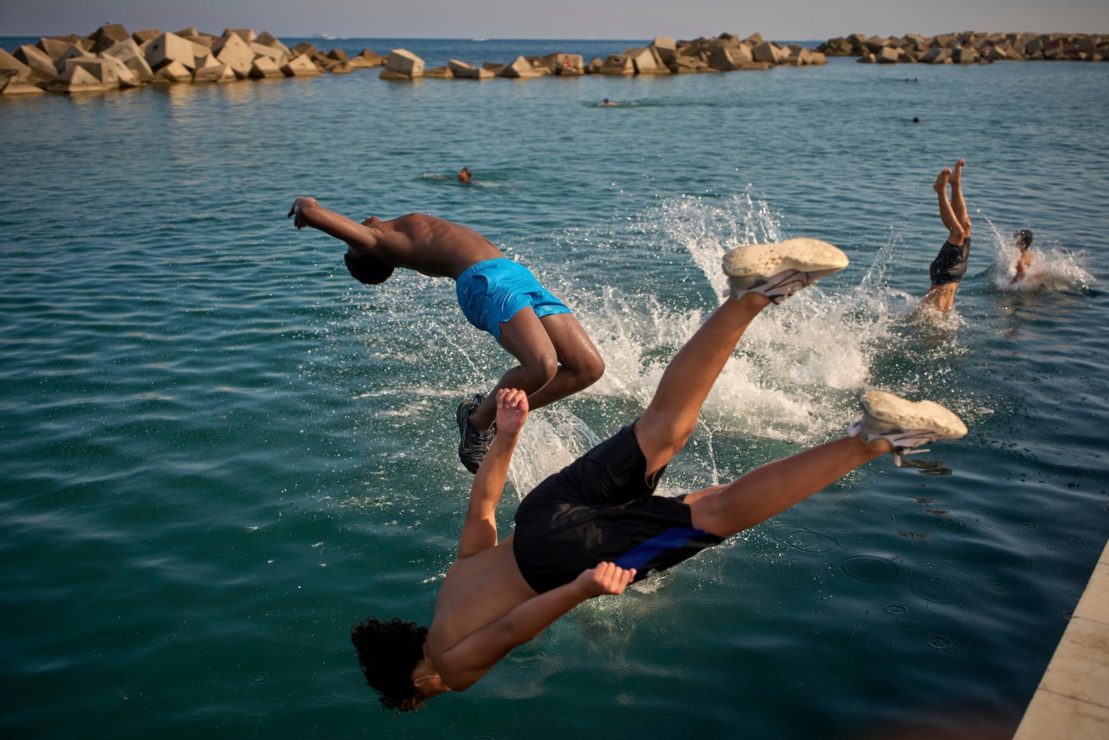Men jump into the water on a hot day in Barcelona, Spain, Tuesday, July 1, 2025. (AP Photo/Emilio Morenatti)