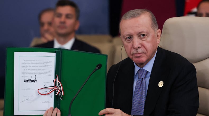Turkey's President Recep Tayyip Erdogan holds a signed document during a summit to support ending the more than two-year Israel-Hamas war in Gaza after a breakthrough ceasefire deal, Monday, Oct. 13, 2025, in Sharm El Sheikh, Egypt. (Suzanne Plunkett/Pool via AP)