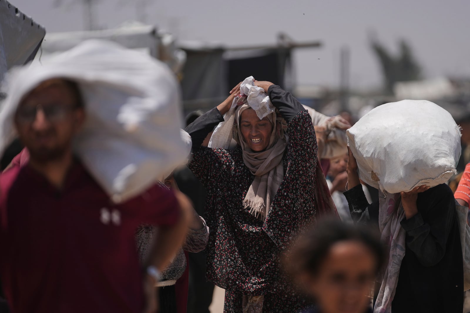 Palestinians carry bags containing food and humanitarian aid packages delivered by the Gaza Humanitarian Foundation, a U.S.-backed organization, in Rafah, southern Gaza Strip, Monday, June 16, 2025. (AP Photo/Abdel Kareem Hana)