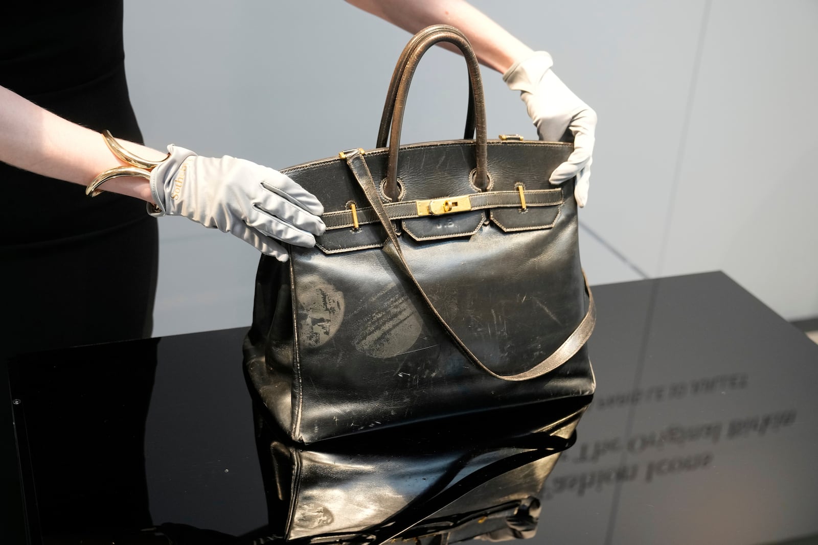 An auction officer displays the original Birkin bag created by Hermès for Jane Birkin in 1984, prior to its auction Thursday, July 10, 2025 in Paris. (AP Photo/Michel Euler)