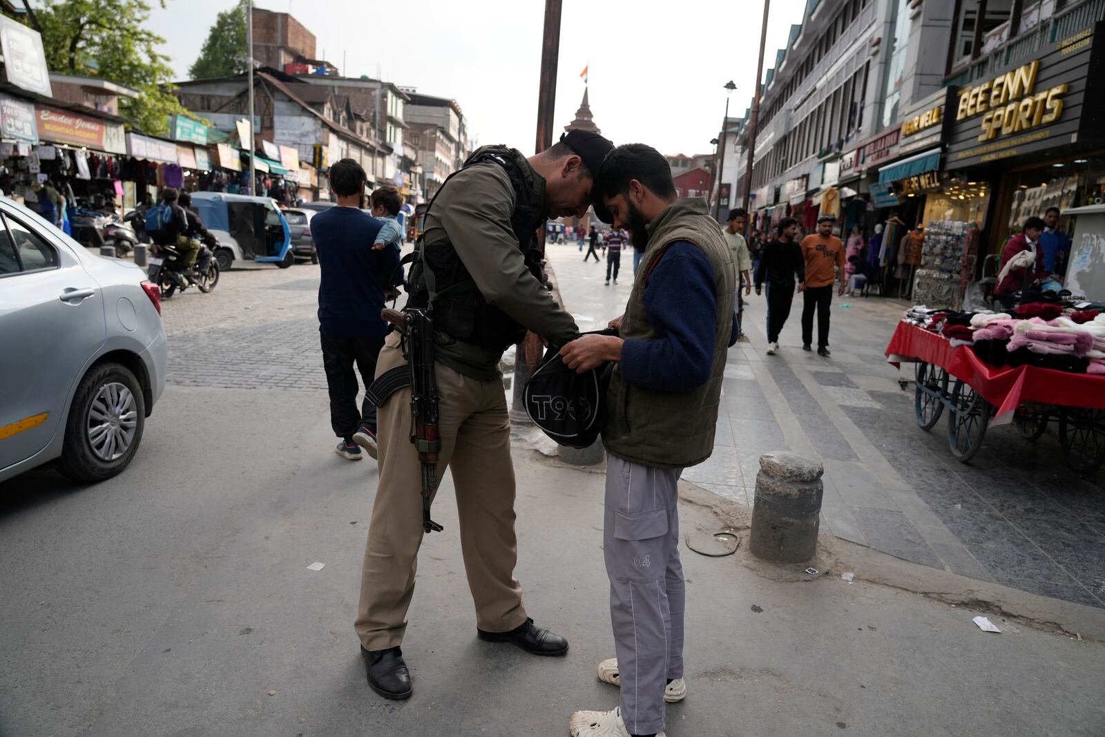 An Indian policeman checks a bag of a civilain near a clock tower at city centre in Srinagar, Indian controlled Kashmir,Tuesday, April. 22, 2025. (AP Photo/Mukhtar Khan)