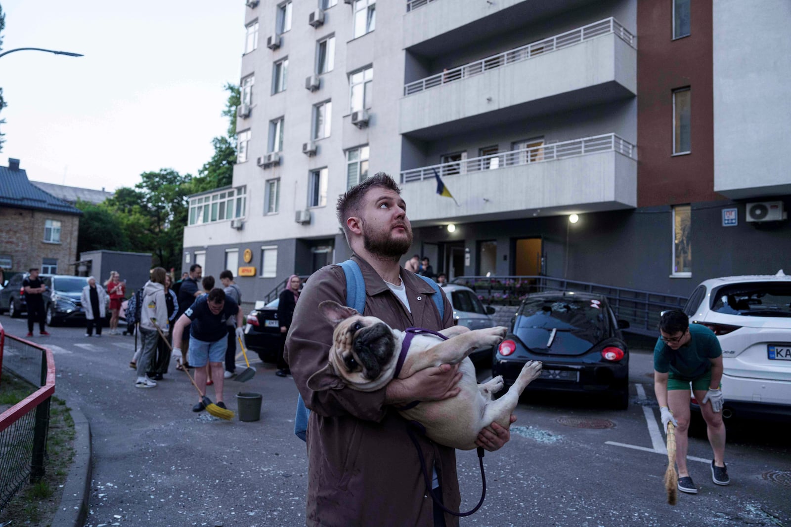 A man carries his dog in front of a residential multi-storey building damaged after a Russian drone strike on Kyiv, Ukraine, on Friday, June 6, 2025. (AP Photo/Evgeniy Maloletka)