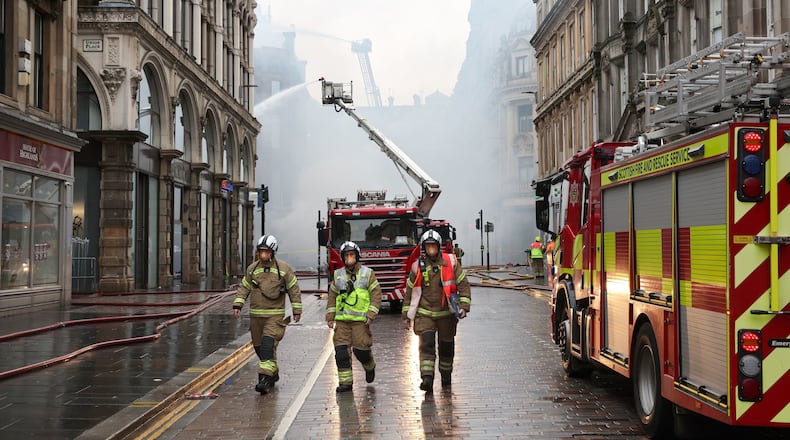 Firefighters damp down the remains of a fire which broke out in a building adjacent to Glasgow Central railway station on Sunday, in Glasgow, Scotland, Monday March 9, 2026. (Robert Perry/PA via AP)