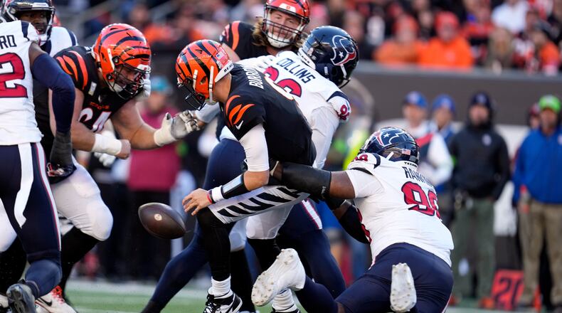Cincinnati Bengals quarterback Joe Burrow, center, fumbles the ball as he is hit by Houston Texans defensive tackle Sheldon Rankins (98) during the second half of an NFL football game Sunday, Nov. 12, 2023, in Cincinnati. The Bengals recovered the fumble. (AP Photo/Michael Conroy)